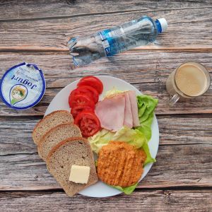 Dieta z ograniczeniem łatwoprzyswajalnych węglowodanów Masło extra Szynka Piastowska Sałata zielona Kawa zbożowa z mlekiem Chleb Graham Jogurt naturalny Hummus paprykowy Woda mineralna Pomidor